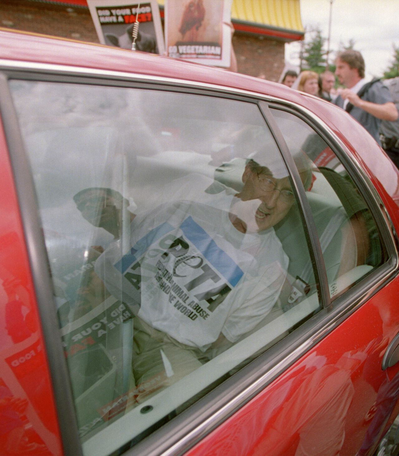 James Cromwell sits in an unmarked police car after being arrested on July 3, 2001, during a demonstration at a Wendy's restaurant in Tysons Corner, Virginia.