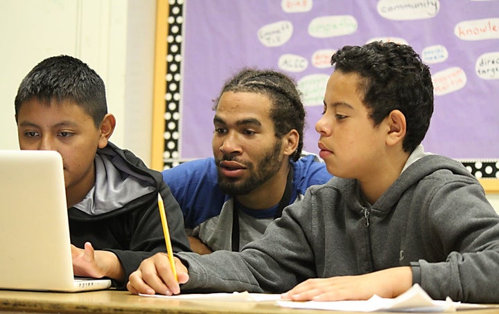 Aim High teacher Malik Beale with 8th grade students who are creating a project on immigration.