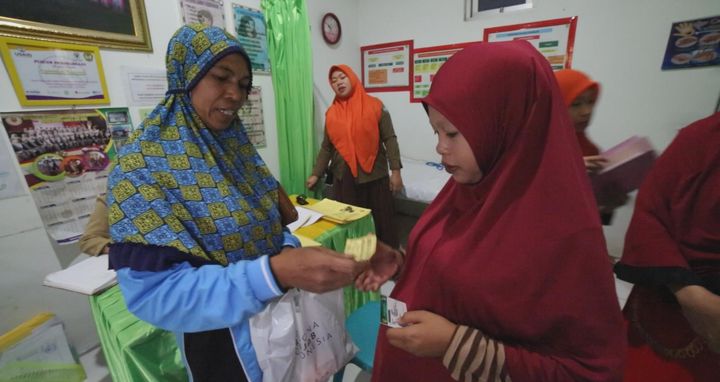Mrs. Rohani, featured in the film, giving a young pregnant women prenatal vitamins as recommended by the local health clinic’s midwife. South Sulawesi, Indonesia.