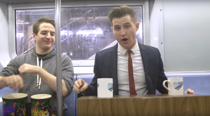 Dean Dimitruk (right) hosts "Derailed," a late night talk show filmed on a New York City subway train. Jeremy Christian (left) plays bongos and is the show's announcer.