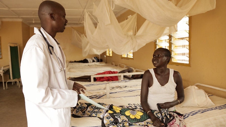 Clinical officer Mark Riongoita speaks with a patient on his rounds in Kacheliba Hospital's specialist kala azar wing in west