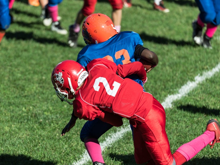 Boys make a tackle during a youth football game. Dr. Bennet Omalu, the man credited with discovering CTE, believes children should not play football.