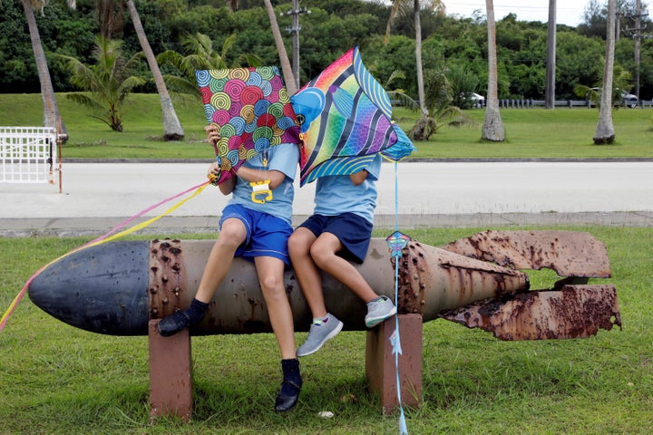 Children sit on the World War II remnants of a torpedo at Asan Memorial Park. 