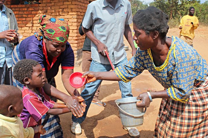 Members of the Mbachundu village Community-based Childcare Development Center provide water for children to wash their hands before eating. Concern provided the center, in Malawi, with a water filter so these children have access to clean water for cleaning and drinking. 