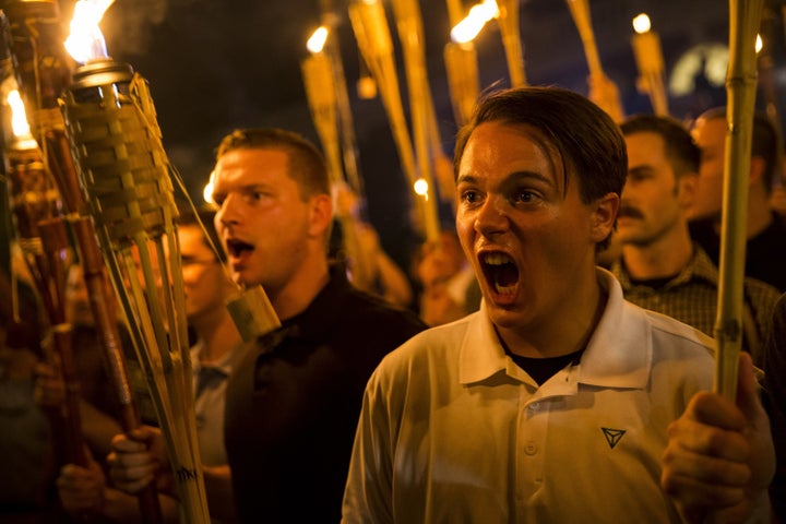 Right-wing protestors shout while holding burning torches aloft