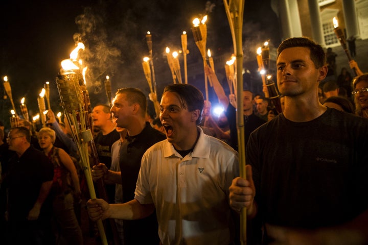 A white woman (far left) protests with a torch at the University of Virginia with neo-Nazis. 