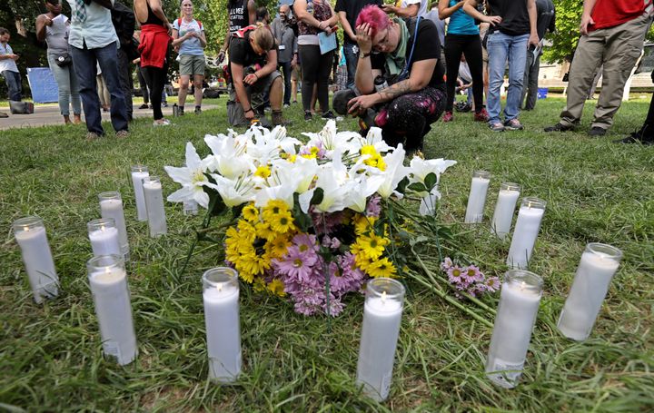 People pay their respects at a vigil where 20 candles were burned for the 19 people injured and one killed when a car plowed into a crowd of counter-protesters at the