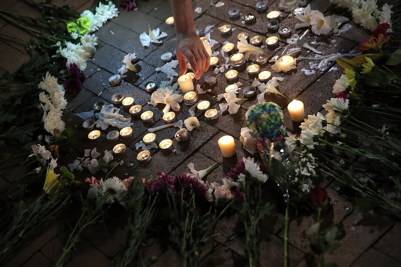 A man tends a makeshift candlelight vigil for those who died and were injured when a car plowed into a crowd of anti-fascist counter-demonstrators marching near a downtown shopping area.