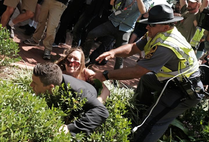 Unite The Right rally organiser Jason Kessler is helped by police after being tackled by a woman after he attempted to speak at a press conference in front of Charlottesville City Hall in Charlottesville, Virginia, August 13.