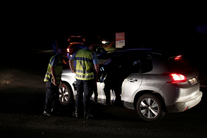 Police stop a car at the roadblock after the incident