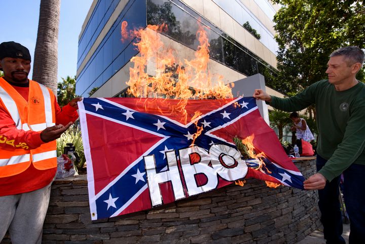Members of Roofers Local 36 stages a protest in front of HBO's Santa Monica offices on Aug. 12. The union's business manager Cliff Smith, right, and member Iyzayra Scott, left, burned a Confederate flag emblazoned with the network's logo in protest of the planned series "Confederate."