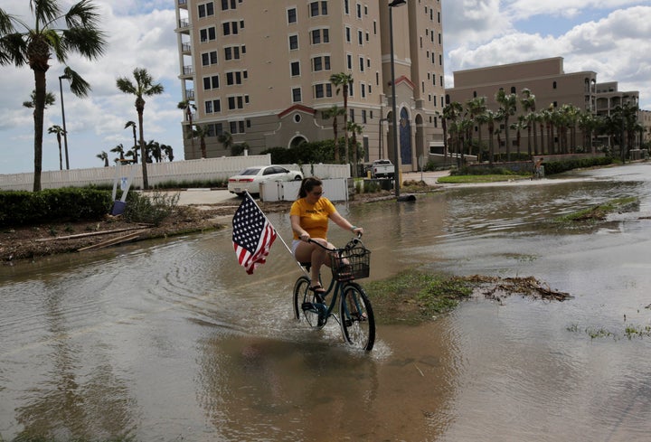 A woman rides her bicycle through a flooded street after Hurricane Matthew, near Jacksonville Beach, Florida, Oct. 8, 2016.