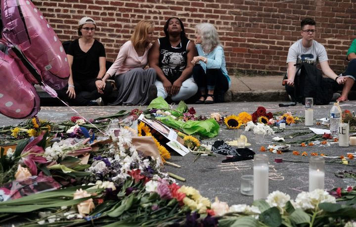 A group sits by a memorial to the victims of the deadly car attack on a group of counter-protesters during a white supremacist rally in Charlottesville, Virginia.