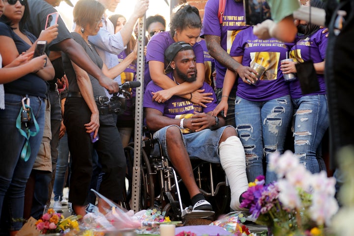 Marcus Martin (center), who was injured when a car plowed into a crowd of people protesting against the white supremacist "Unite the Right" rally, his fiancée, Marissa Blair (behind with arms around Marcus), and friends visit the memorial built at the place where he was injured and where 32-year-old Heather Heyer was killed in the same attack.