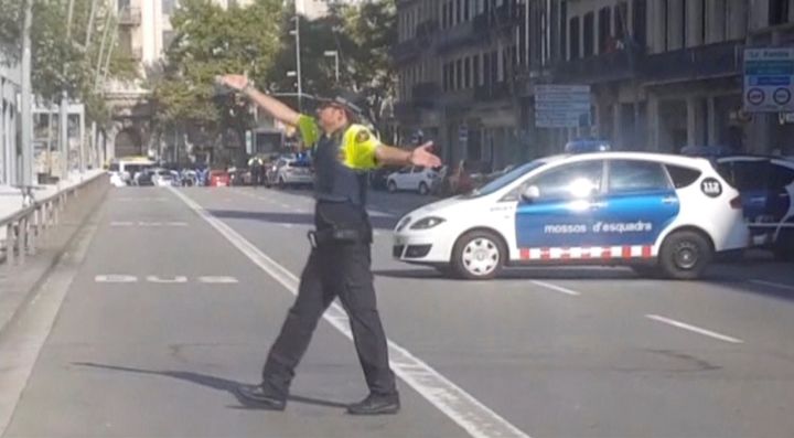 A still image from video shows a police officer gesturing while walking across a road, after a van crashed into people in the centre of Barcelona