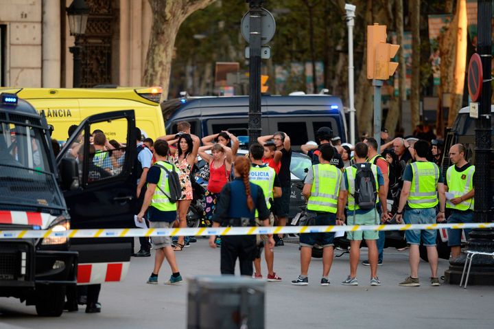Policemen check the identity of people standing with their hands up after a van ploughed into the crowd at Las Ramblas.