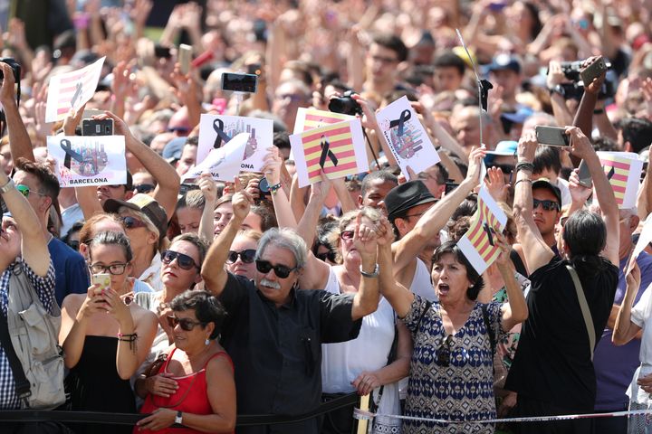 People hold banners as they observe a minute of silence in Placa de Catalunya in Barcelona