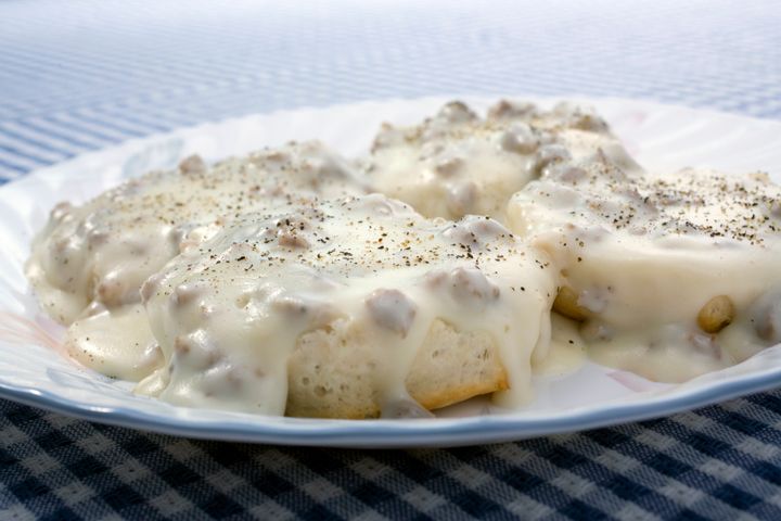 A photo of biscuits & gravy on a white plate.