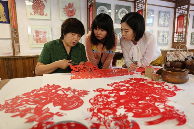 Tourists are learning one of the traditional paper cutting techniques in Chengde, Hebei province, China./ Source: Xinhua News, Yonhap