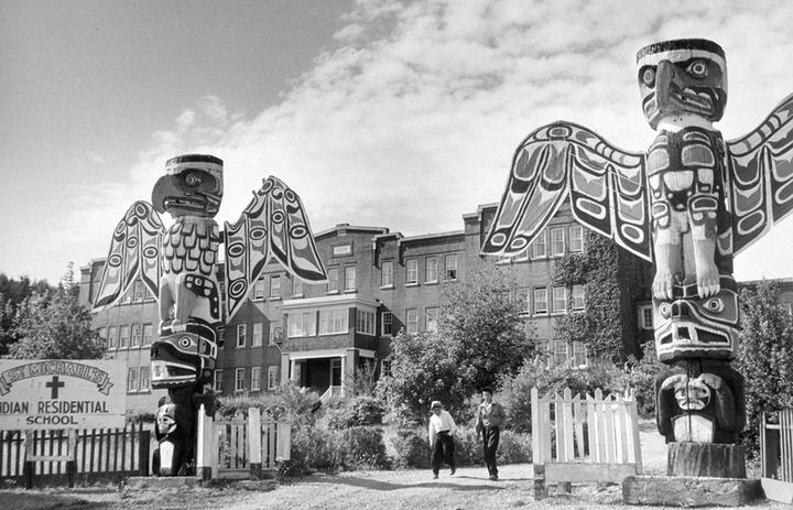 Students walk between two totem poles at St. Michael's Indian Residential School in Alert Bay, British Columbia, in a 1970 photo.