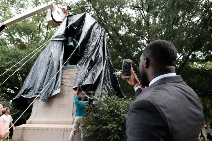 The statue of Confederate General Thomas "Stonewall" Jackson is shown covered in black tarp as Dr. Wes Bellamy, the vice mayor of Charlottesville, takes a photo in the Virginia city on Wednesday.