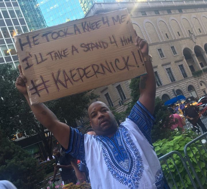 A man stands with a handmade sign supporting former 49ers quarterback Colin Kaepernick.