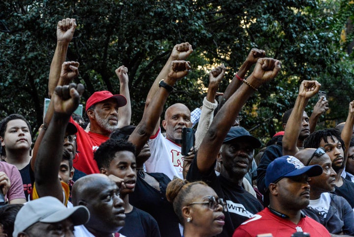 Rally attendees stand, fists raised, expressing solidarity with former San Francisco 49er Colin Kaepernick in his quest for racial justice.