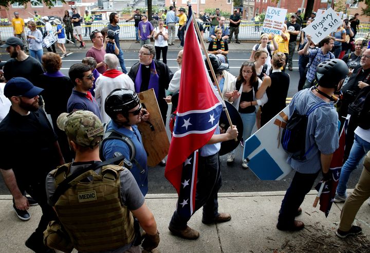 A white nationalist carries the Confederate flag as he walks past counter-demonstrators in Charlottesville, Virginia, on Aug. 12