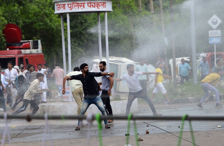 Supporters of Indian religious leader Gurmeet Ram Rahim Singh throw stones at security forces as they are sprayed with a wate