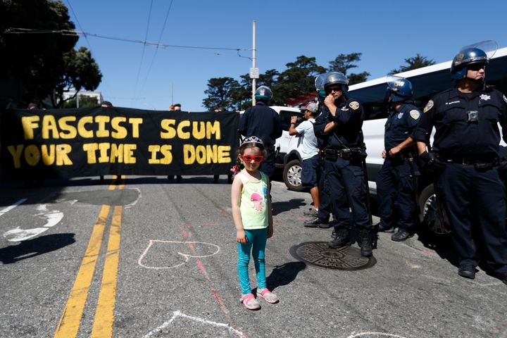 A child stands next to a line of police officers by San Francisco's Alamo Square as demonstrators rally ahead of a news conference by the organizers of the canceled rally on Aug. 26, 2017.