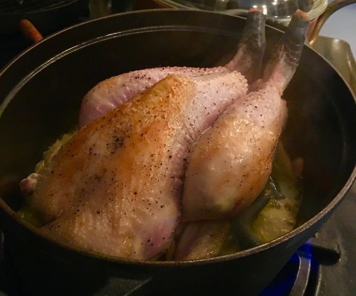 The browned chicken set over the aromatics, wine and stock 