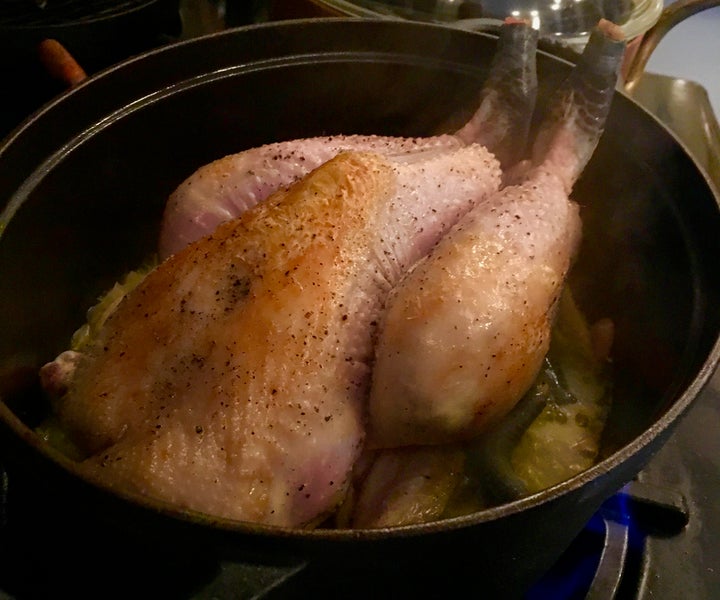 The browned chicken set over the aromatics, wine and stock