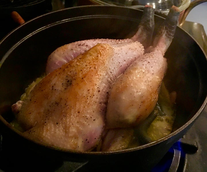 The browned chicken set over the aromatics, wine and stock 