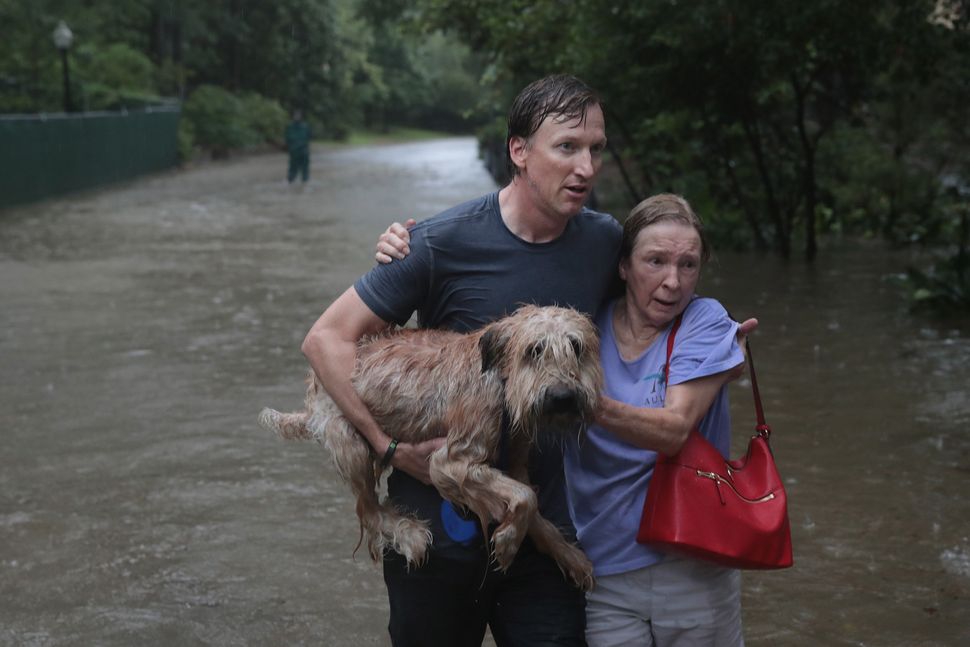 Andrew White (left) helps a neighbor down a street after rescuing her in his boat in Houston's River Oaks neighborhood.