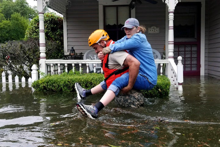 In this photo provided by the Army National Guard, a Texas National Guardsman carries a resident from her flooded home following Hurricane Harvey on Aug. 27 in Houston.