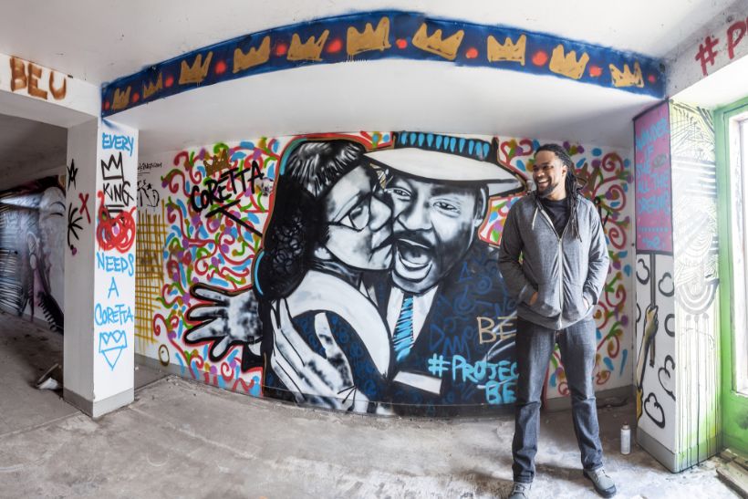 Brandan Odums in front of a portrait of Coretta Scott King and Martin Luther King Jr. in his