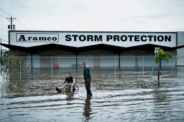 Brad Matheney helps a man in a wheelchair navigate a flooded street in Galveston, Texas, on Saturday.