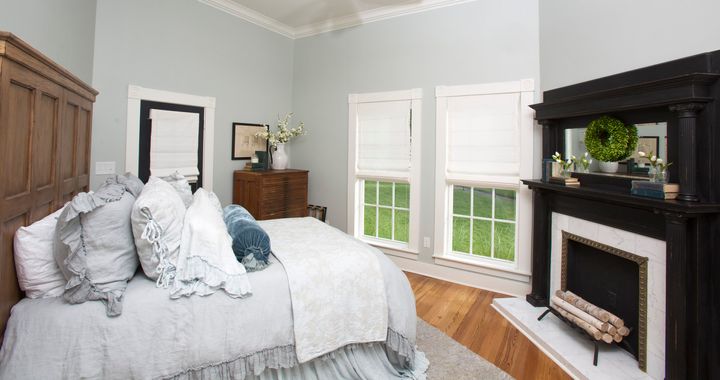 This downstairs bedroom features hardwood floors, cool gray wall paint and a restored fireplace.
