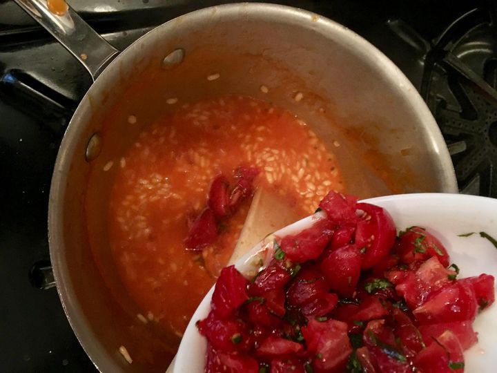 When the rice is nearing doneness, in go the quartered cherry tomatoes and basil