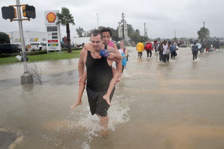 People make their way out of a flooded neighborhood after it was inundated with rain water, remnants of Hurricane Harvey, on August 28, 2017 in Houston, Texas.