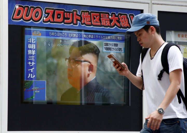 A man walks past a TV set showing North Korea's leader Kim Jong-Un in a news report about North Korea's missile launch in Tok