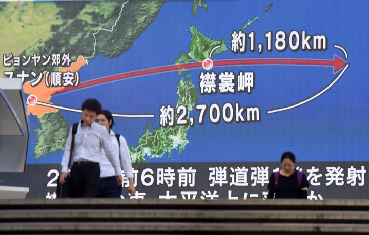 Pedestrians walk in front of a huge screen displaying a map of Japan and the Korean Peninsula after the missile launch