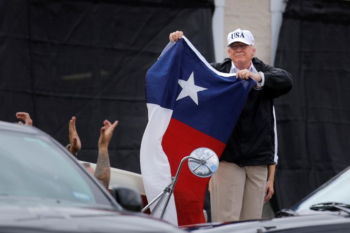 Trump holds a flag of the state of Texas after receiving a briefing on Harvey relief effort in Corpus Christi.