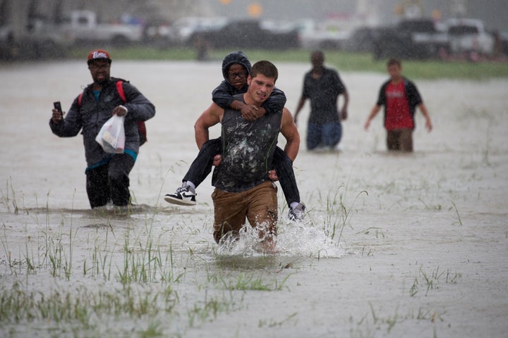 A man wades through flood waters from Tropical Storm Harvey while helping evacuate a boy in east Houston on Monday.