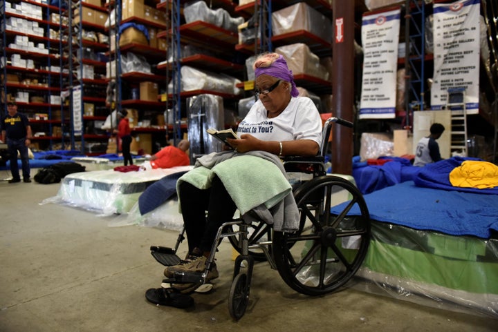 Charlotte Mills reads her Bible in Gallery Furniture's warehouse on Tuesday after evacuating her flooded home.