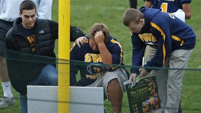 <p>Students in Shoreham, New York, pause at a makeshift memorial to Tom Cutinella, a 16-year-old varsity football player who died after a collision in 2014. States are trying to reduce risks to their student-athletes, but some may have a long way to go.</p>