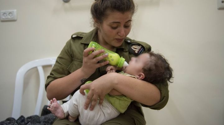 <p><em>In an undated photo provided on July 19, 2017, an IDF soldier feeds a Syrian baby in Israel as part of Operation Good Neighbor</em></p>