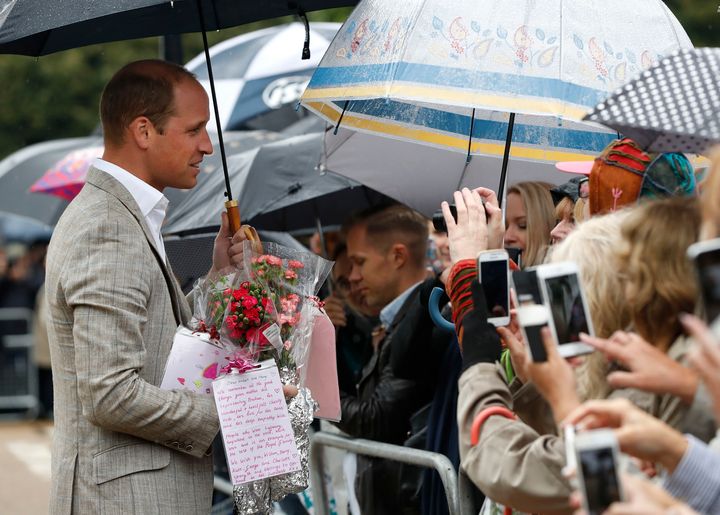 The Duke of Cambridge is given flowers by members of the public which he then placed amongst the tributes to Diana.