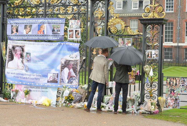 The Duke of Cambridge (left) and Prince Harry look at tributes to Diana, Princess of Wales attached to the Golden Gates of Kensington Palace, London, ahead of the 20th anniversary of their mother's death.