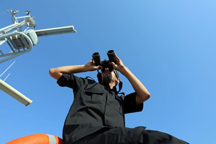 A member of the Libyan Coast Guard uses a pair of binoculars as he searches for migrants off the coast of Tripoli, Libya, 9 August.